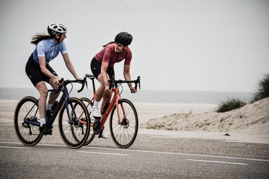 Two girls cycling along a road chatting