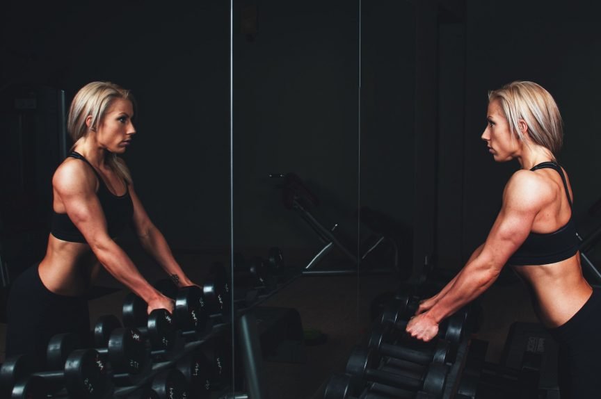 A girl looking at herself whilst weightlifting